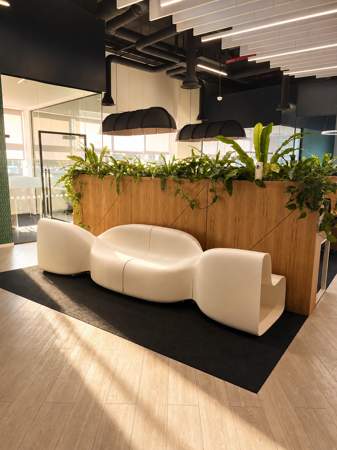 White modular 3D-printed seating installed in a bright office with a living plant wall