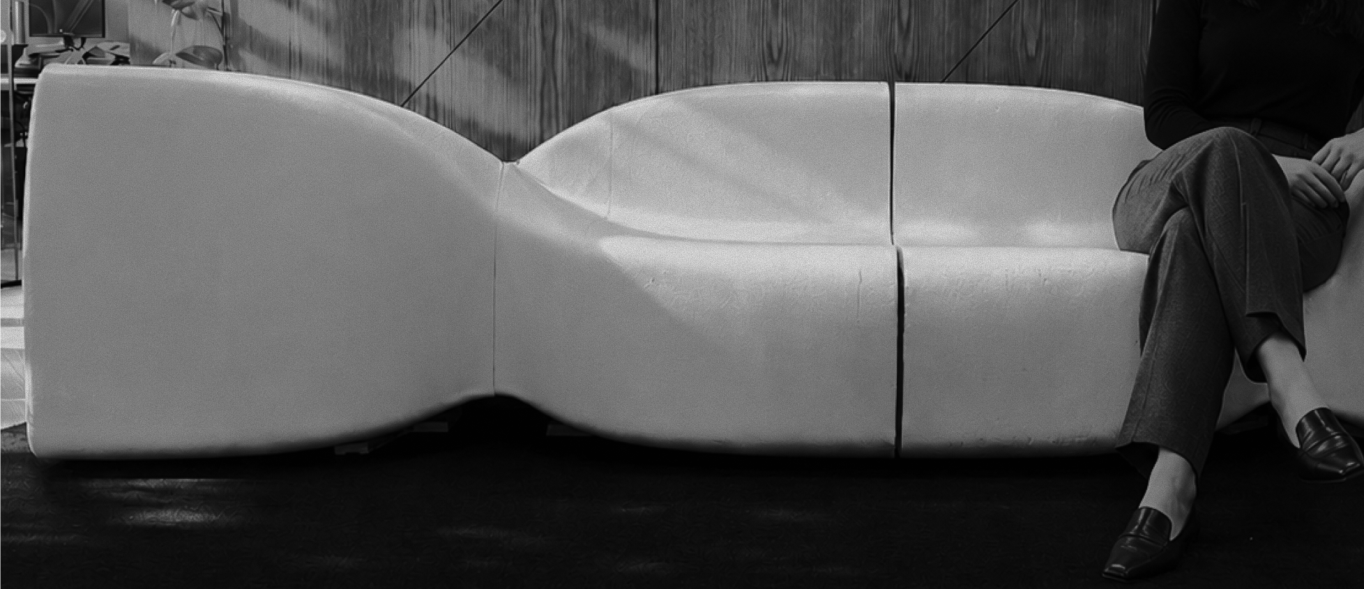 Person seated on a long white 3D printed modular bench with a curved pinched profile